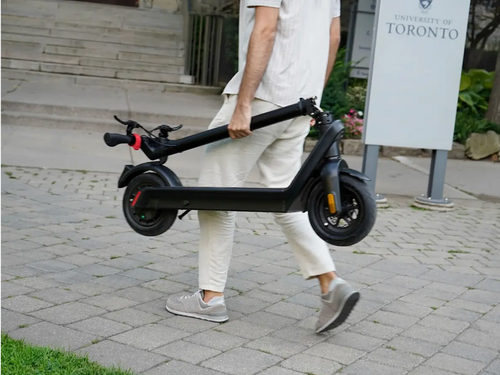 Person carrying folded Movin Glide Electric Scooter for portable urban commuting