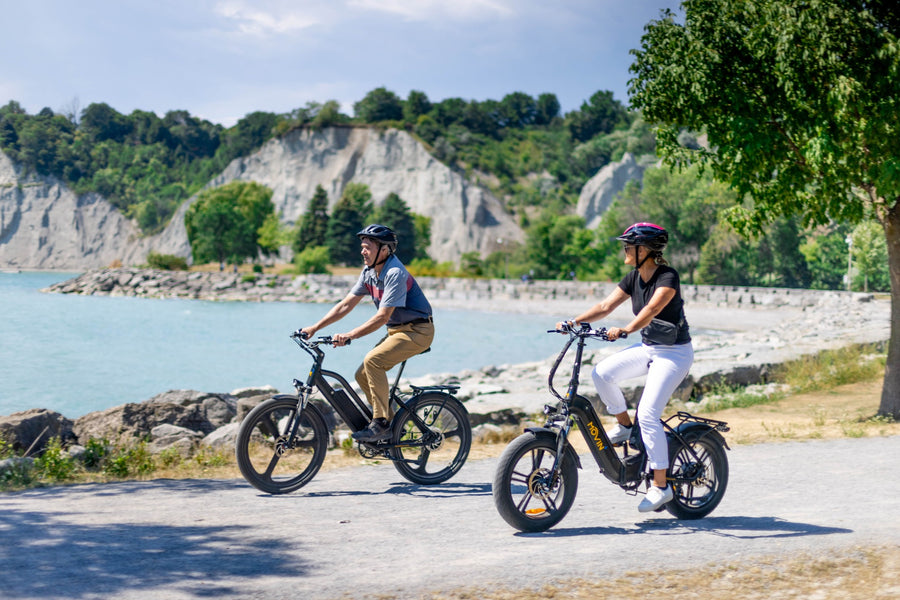Cyclists with Movin electric bikes relaxing at lakeshore on a nature ride